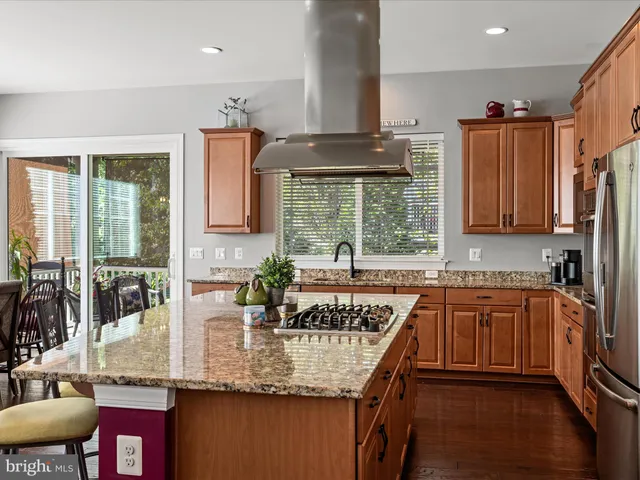 a kitchen with stainless steel appliances kitchen island granite countertop a refrigerator and wooden cabinets