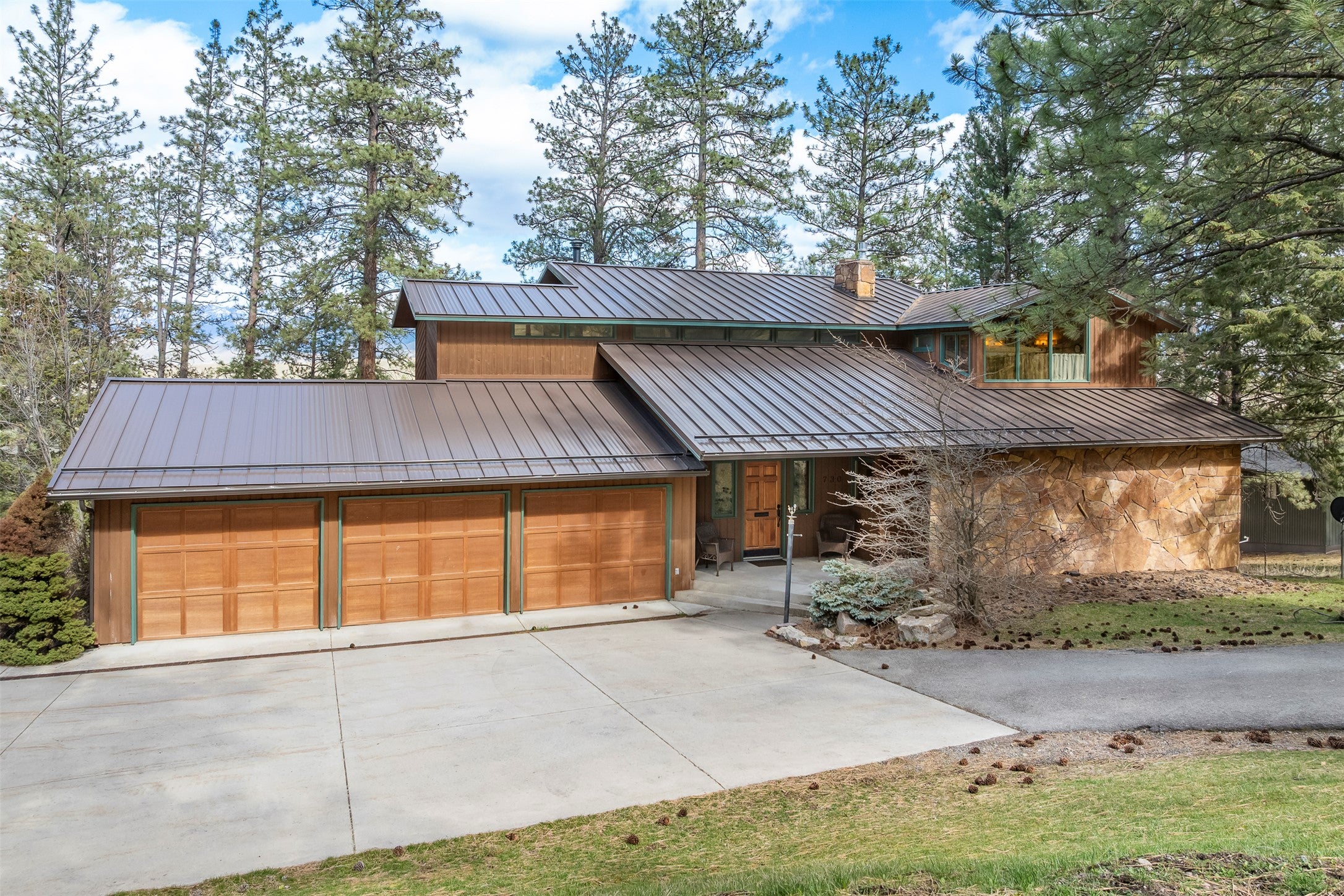 730 Big Flat Road Missoula, MT 59804 - Photo 4 of 59 View of front facade featuring a standing seam roof, an attached garage, driveway, and a chimney