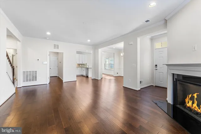 a view of an empty room with wooden floor and a fireplace