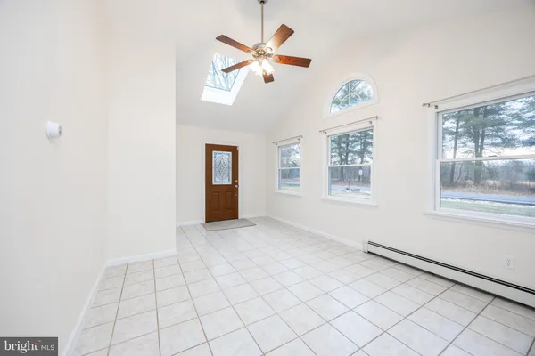 a view of an empty room with window and chandelier fan