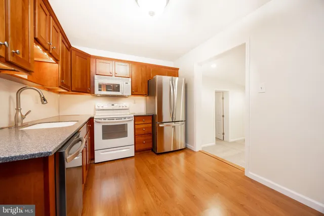 a kitchen with stainless steel appliances granite countertop a refrigerator a stove and a sink