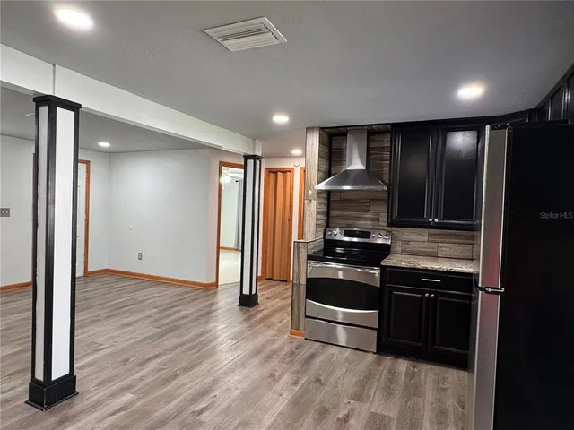 an empty room with wooden floor and kitchen view