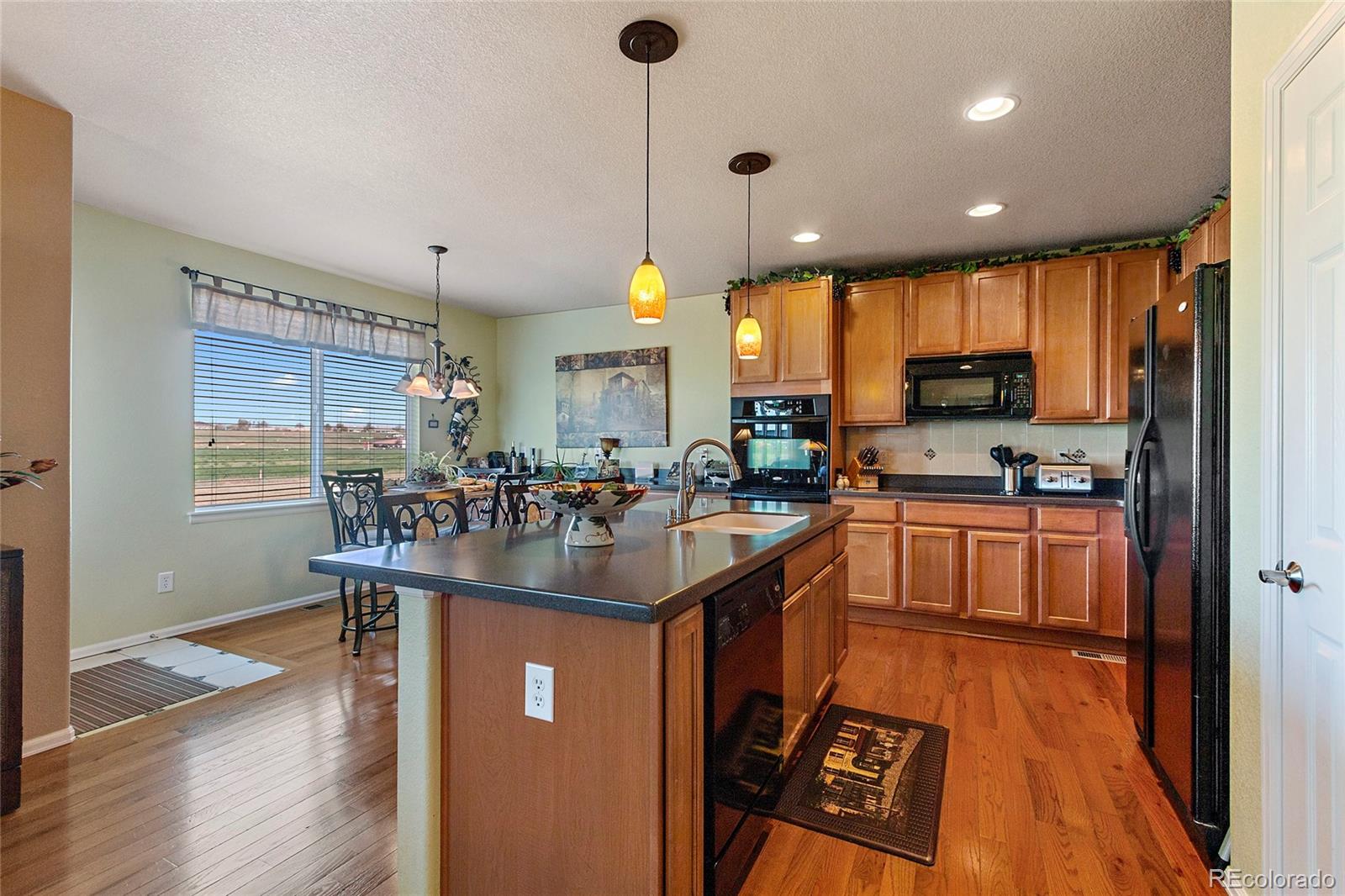 8151 Raspberry Drive Frederick, CO 80504 - Photo 6 of 35 a kitchen with stainless steel appliances granite countertop a refrigerator a sink dishwasher a stove and a dining table with wooden floor
