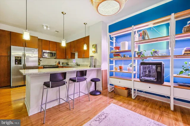a view of a kitchen with kitchen island a large counter top space a sink stainless steel appliances and cabinets