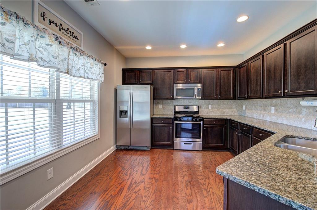 25 Winter Pointe Northwest Cartersville, GA 30121 - Photo 12 of 43 a kitchen with stainless steel appliances granite countertop a refrigerator a sink dishwasher a stove and wooden cabinets with wooden floor