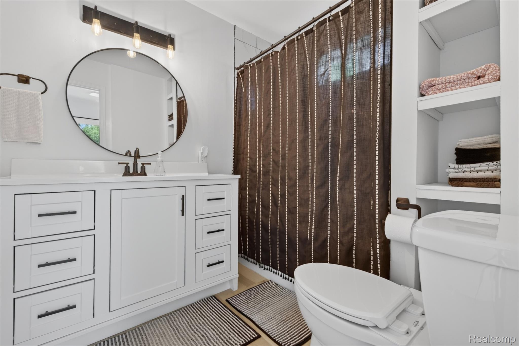 5244 Oleksyn Road Flint, MI 48504 - Photo 22 of 70 Bathroom featuring a white vanity with integrated sink, a circular mirror, and a three-light vanity fixture