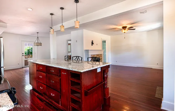 a view of kitchen with kitchen island a wooden floor and a view of living room