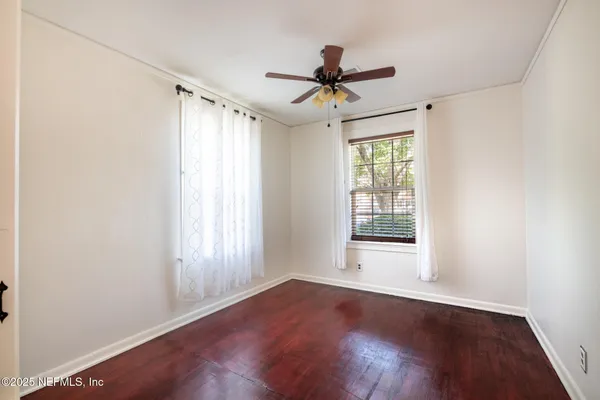 a view of empty room with wooden floor and fan