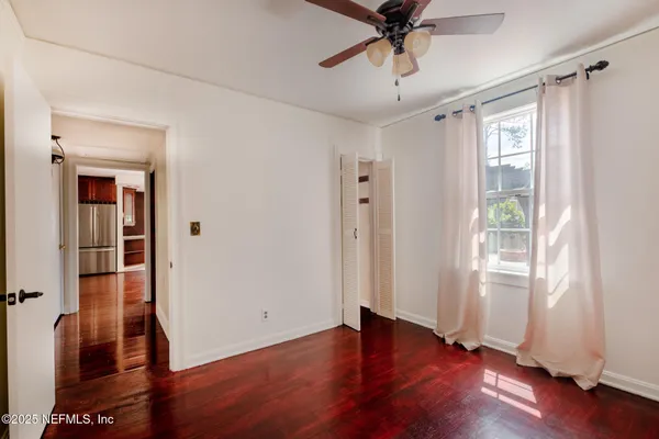 an empty room with wooden floor fan and windows