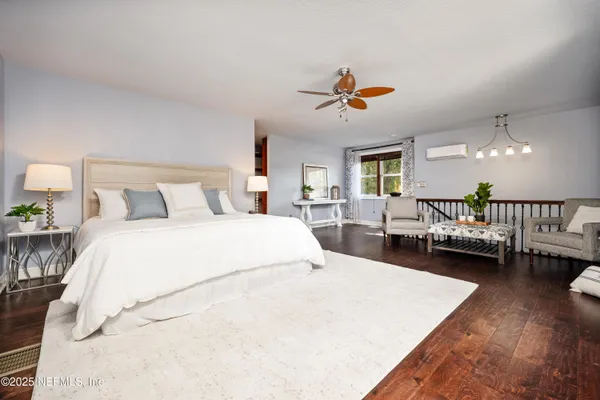 a bedroom with a bed a couch and wooden floor
