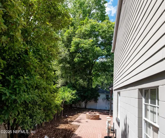 a backyard of a house with wooden fence and large trees