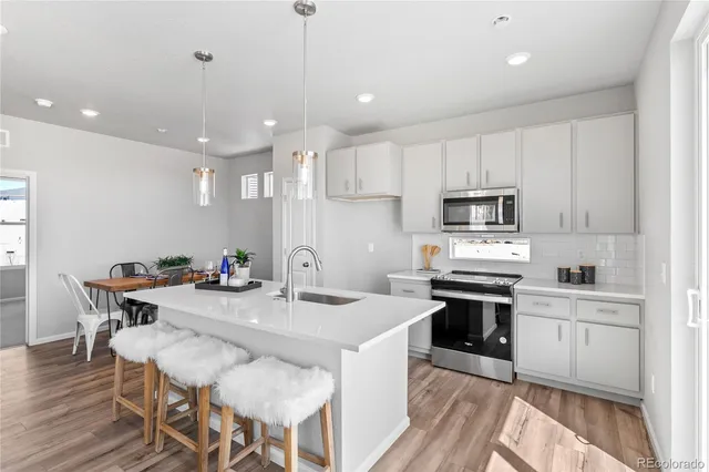 a kitchen with stainless steel appliances kitchen island granite countertop a stove a sink a dining table and chairs with wooden floor