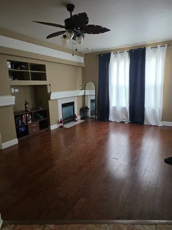 a view of a livingroom with wooden floor a fireplace and window