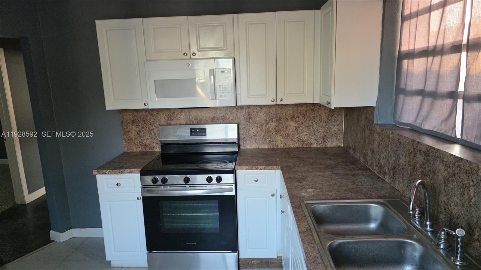 3300 Northwest 23rd Avenue, Unit 1 Miami, FL 33142 - Photo 4 of 11 a kitchen with granite countertop a stove sink and cabinets