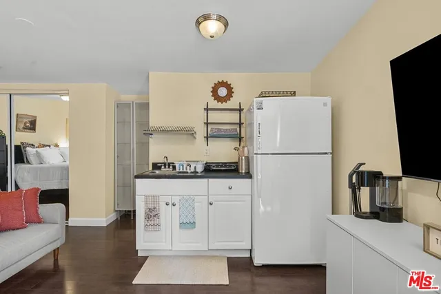a kitchen with granite countertop a refrigerator a sink and white cabinets