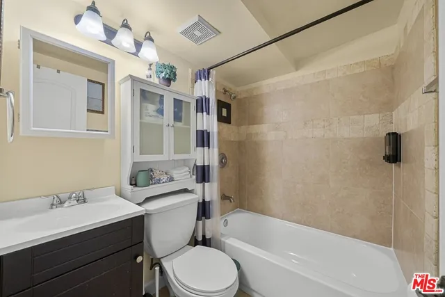 a bathroom with a sink a toilet a mirror a vanity a bathtub and shower
