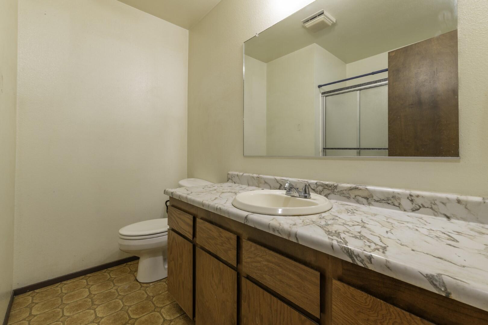3305 Cessna Drive Redding, CA 96001 - Photo 11 of 15 a bathroom with a granite countertop sink a toilet and a mirror