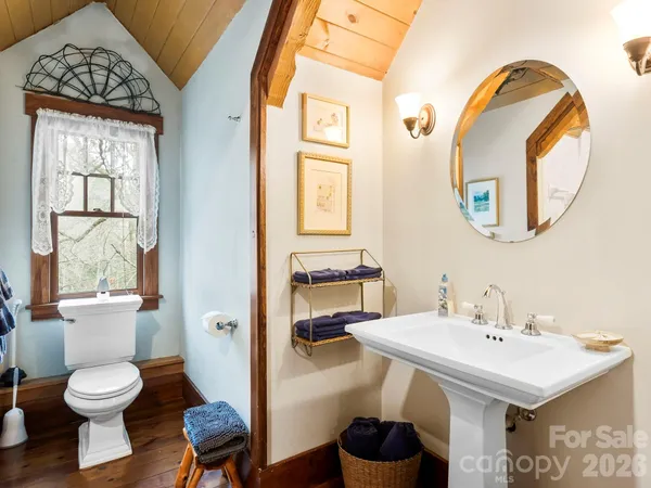 a bedroom with a bed a table and chair with the wooden floor