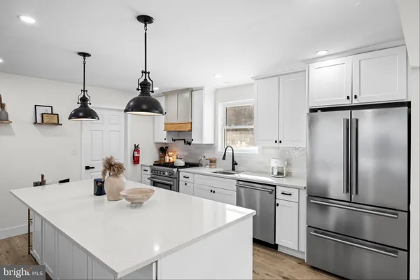 a kitchen with stainless steel appliances a sink a refrigerator a center island and cabinets