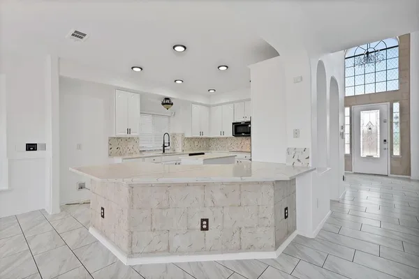 a large white kitchen with kitchen island a sink a counter space and cabinets