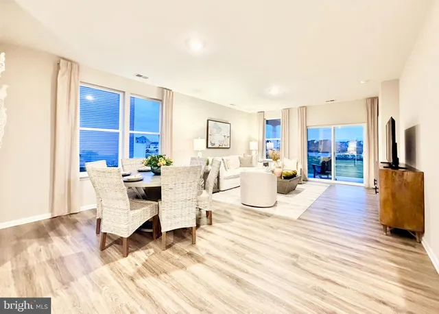 a living room with furniture a kitchen view and a wooden floor