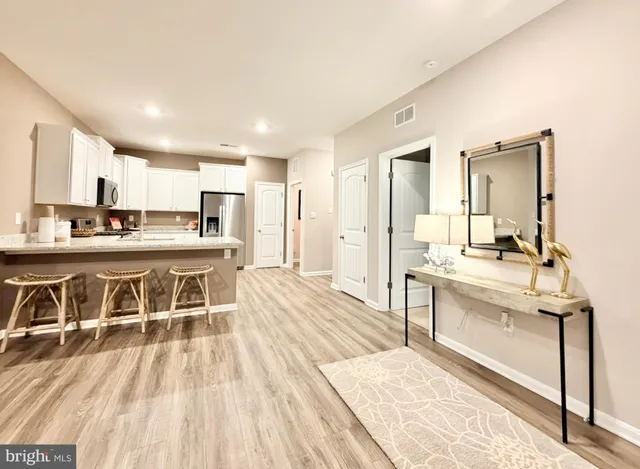 a living room with stainless steel appliances kitchen island granite countertop a sink and cabinets