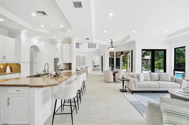 a large living room with stainless steel appliances kitchen island granite countertop a couch and a view of living room