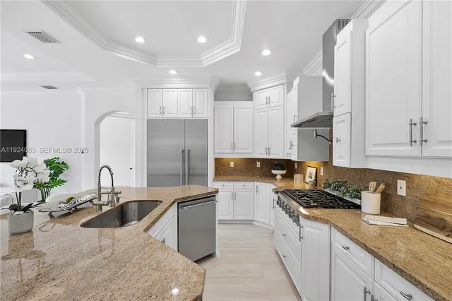 a kitchen with stainless steel appliances granite countertop a sink a stove and a refrigerator