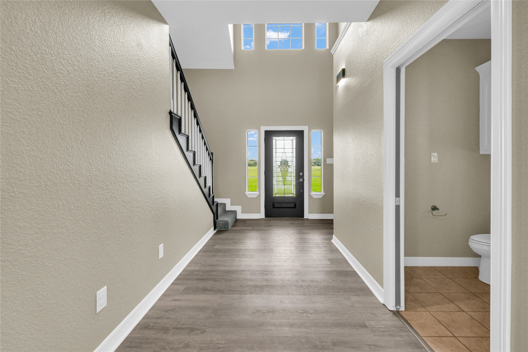 863 Bunkhouse Trail Angleton, TX 77515 - Photo 2 of 22 This entryway features a high ceiling with abundant natural light from upper windows and a convenient half-bathroom.