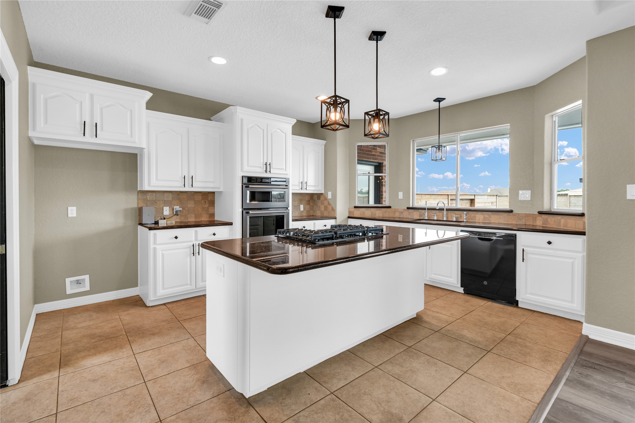 863 Bunkhouse Trail Angleton, TX 77515 - Photo 5 of 22 This modern kitchen features sleek white cabinetry, a central island with a gas cooktop, and stylish pendant lighting. It has ample natural light from large windows and offers stainless steel appliances for a contemporary look.