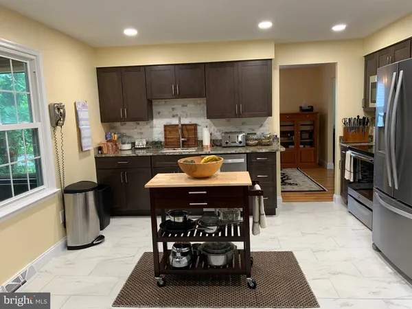 a kitchen with a refrigerator a stove a sink a dining table and chairs