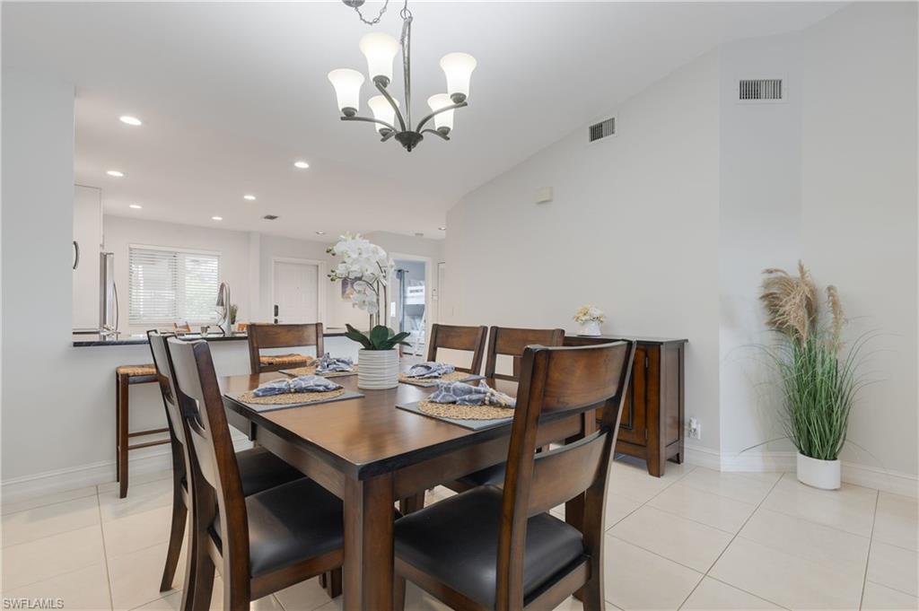 7766 Emerald Circle, Unit R203 Naples, FL 34109 - Photo 11 of 30 Dining space with vaulted ceiling, light tile patterned flooring, recessed lighting, and a chandelier