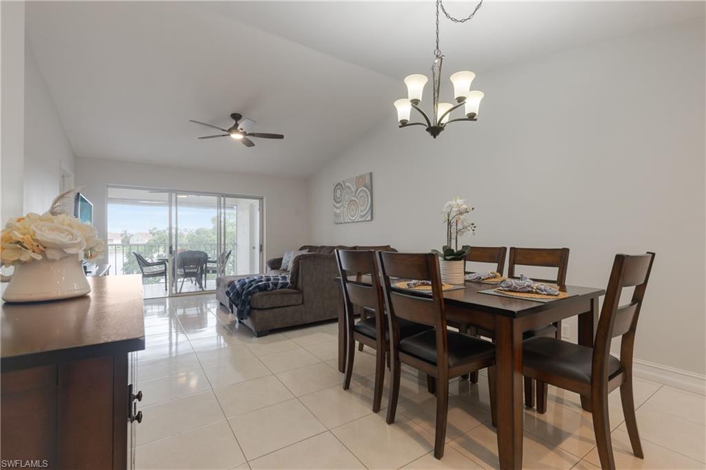 7766 Emerald Circle, Unit R203 Naples, FL 34109 - Photo 12 of 30 Dining room with light tile patterned flooring, ceiling fan, vaulted ceiling, and a chandelier