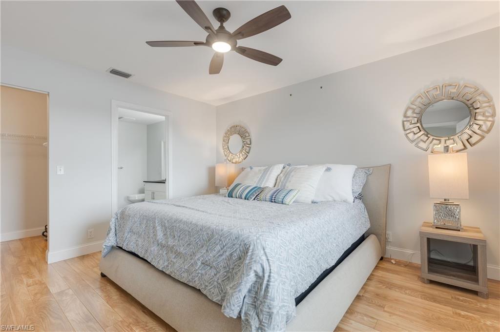 7766 Emerald Circle, Unit R203 Naples, FL 34109 - Photo 17 of 30 Bedroom with light wood-style floors, a spacious closet, a ceiling fan, and ensuite bath