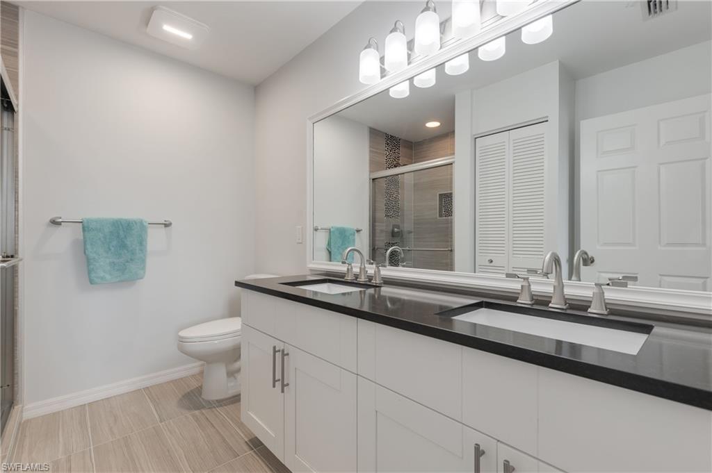 7766 Emerald Circle, Unit R203 Naples, FL 34109 - Photo 21 of 30 Bathroom featuring a stall shower, double vanity, and a closet