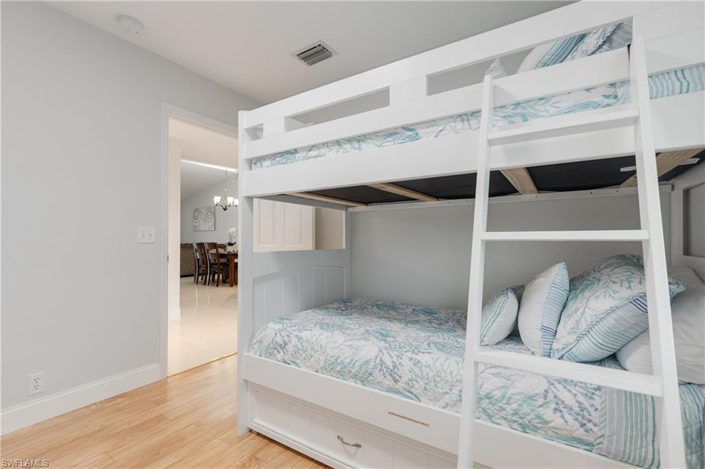 7766 Emerald Circle, Unit R203 Naples, FL 34109 - Photo 23 of 30 Bedroom with wood finished floors and a chandelier