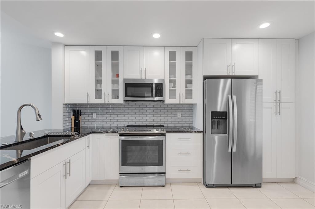 7766 Emerald Circle, Unit R203 Naples, FL 34109 - Photo 4 of 30 Kitchen with stainless steel appliances, tasteful backsplash, dark stone counters, white cabinets, and recessed lighting