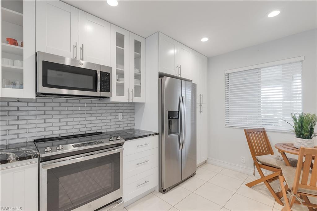 7766 Emerald Circle, Unit R203 Naples, FL 34109 - Photo 6 of 30 Kitchen featuring appliances with stainless steel finishes, glass insert cabinets, white cabinets, dark stone counters, and recessed lighting
