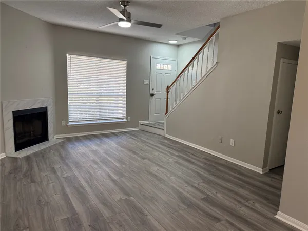 a view of an empty room with wooden floor fireplace and a window