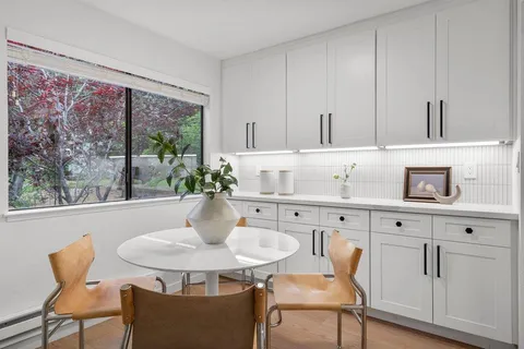 a kitchen with stainless steel appliances kitchen island a table and chairs in it
