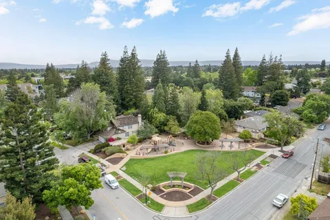 an aerial view of a residential houses with outdoor space and trees all around