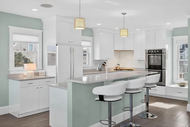 a large kitchen with kitchen island white cabinets and stainless steel appliances