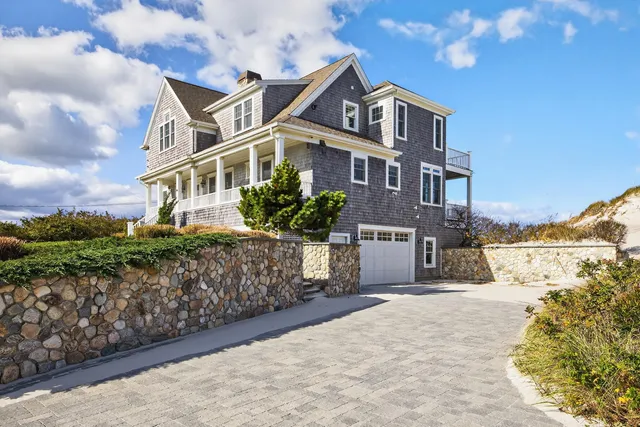 a front view of a house with a yard and potted plants