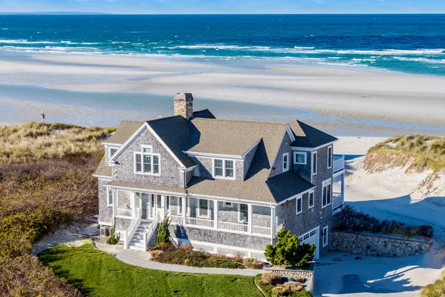 a front view of a house with a garden and lake view