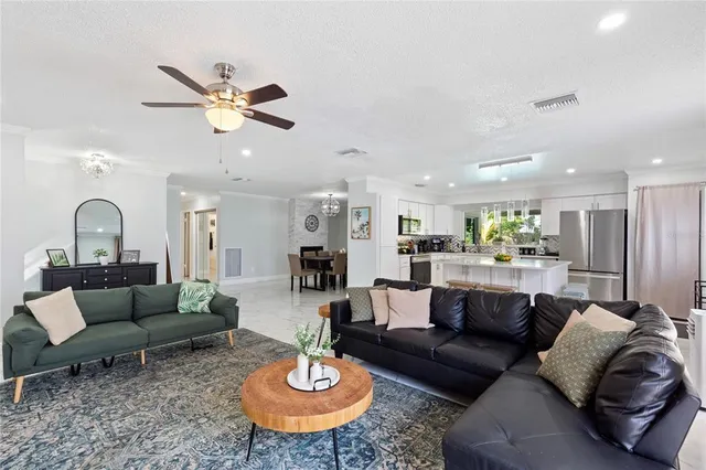 a living room with furniture kitchen view and a chandelier