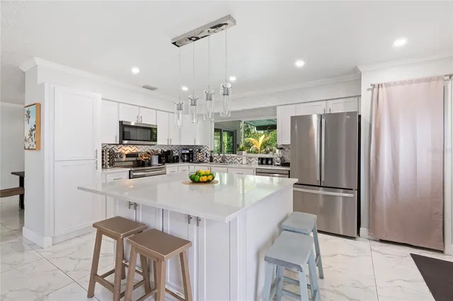 a kitchen with a refrigerator a stove a sink and chairs