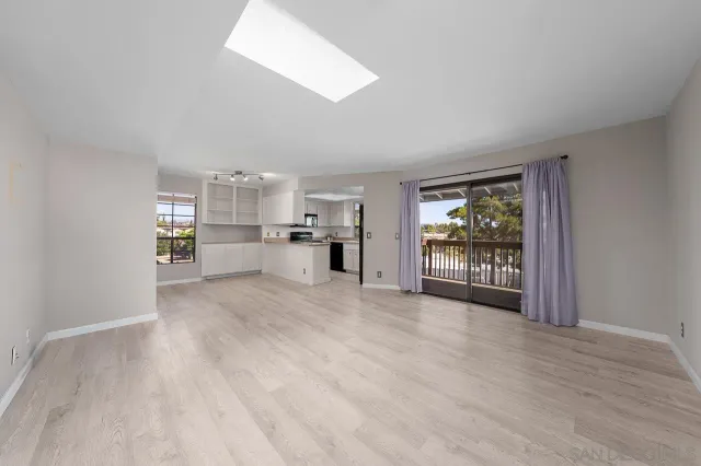 a view of empty room with wooden floor and a window