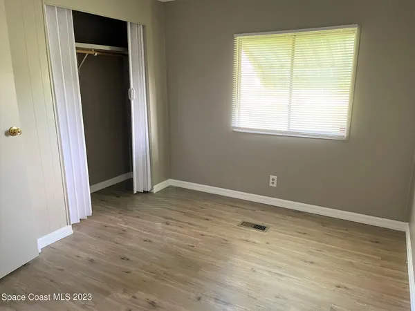 a kitchen with a refrigerator a stove top oven a sink and white cabinets with wooden floor