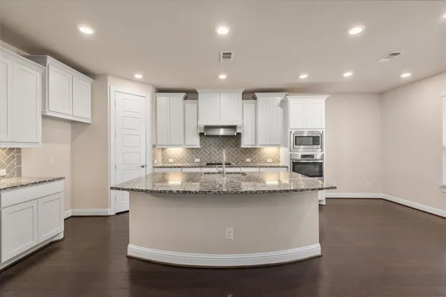 a kitchen with granite countertop white cabinets and white stainless steel appliances