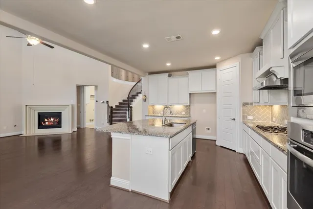 a kitchen with stainless steel appliances granite countertop a sink stove and cabinets